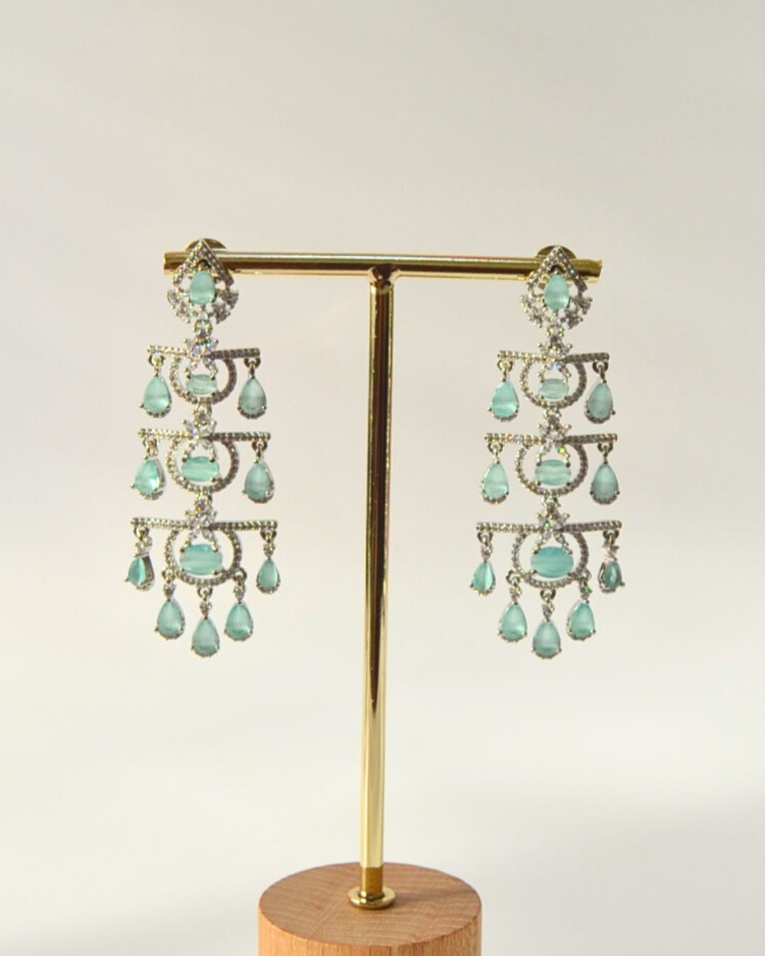 Pair of turquoise chandelier earrings on a gold stand with a white background