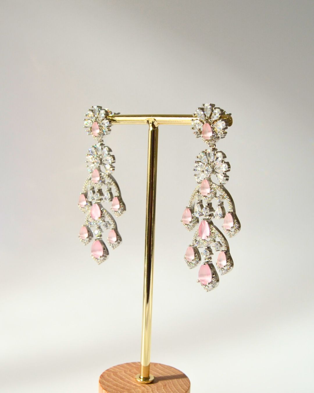 Pair of earrings on a gold stand with a light gray background
