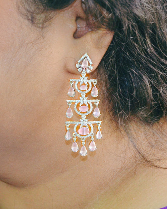 Close-up of a person wearing a decorative chandelier earring with pink gemstones.