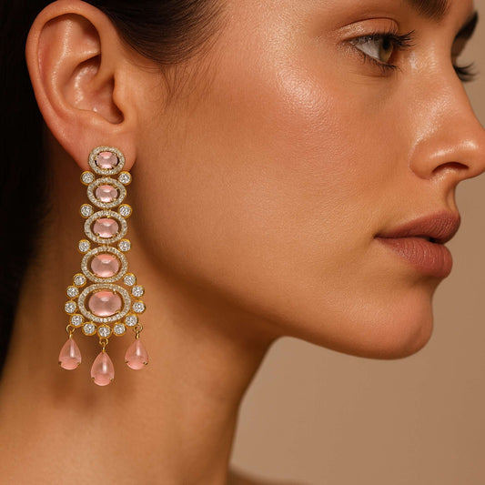 Close-up of a woman wearing a pink and gold earring against a neutral background
